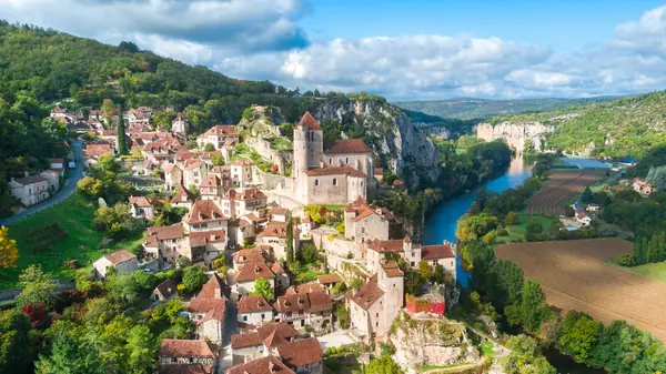 Aerial view of the medieval village of Saint-Cirq-Lapopie with red-tiled roofs and a fortified church on a cliff above the river Lot