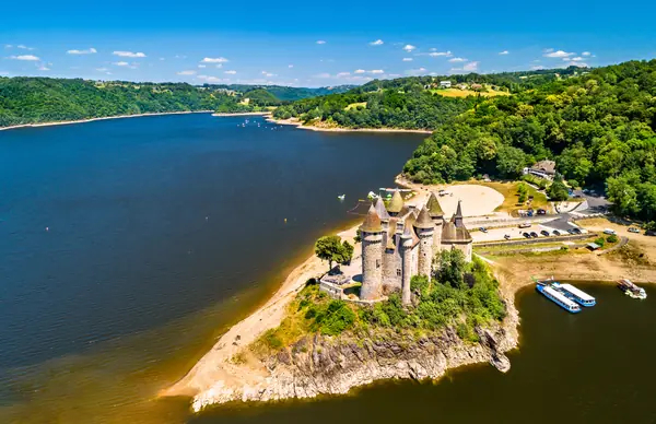 Aerial view of the turreted Chateau de Val on a rocky promontory in a lake on the upper Dordogne river, surrounded by wooded hills