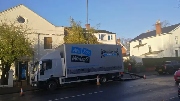 Gentlevan Removals lorry with its tail lift down and cones set out on a UK residential street during a house move