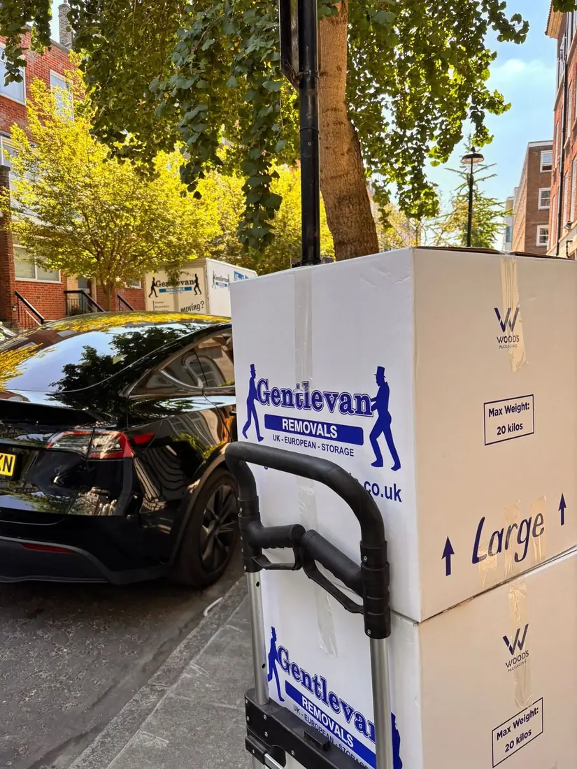 Gentlevan cartons on a sack truck being wheeled from a property to the vehicle on a tree lined street