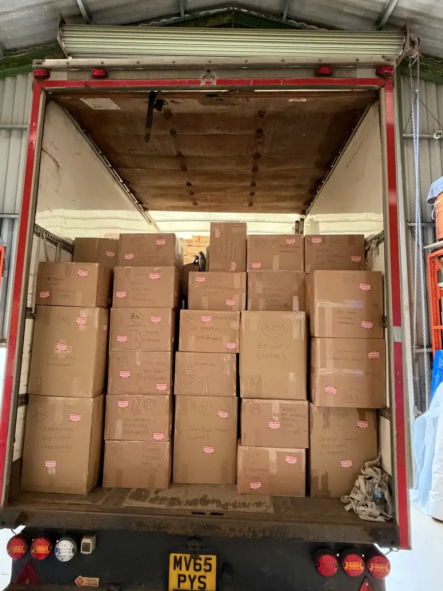 Removal cartons stacked in the back of a Gentlevan lorry, each one numbered and marked with its contents