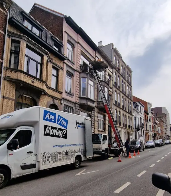 Gentlevan Removals Luton van parked on a residential street in the Netherlands while household furniture is moved into an upper-floor apartment using an external furniture lift beside traditional Dutch townhouses.