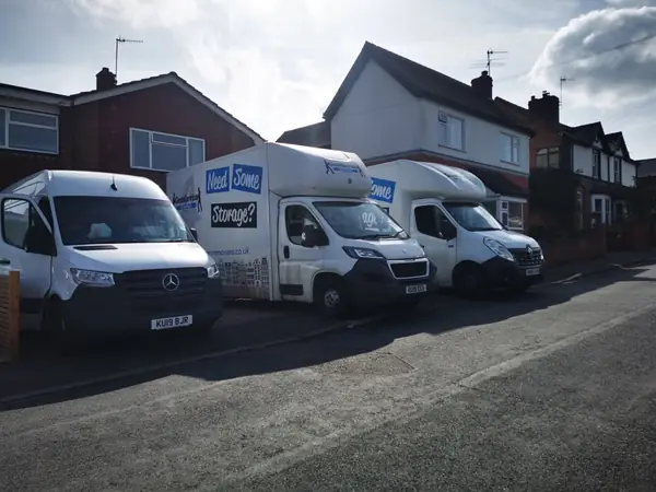Three Gentlevan removal vans parked nose to tail on a residential street outside a pair of semi-detached houses