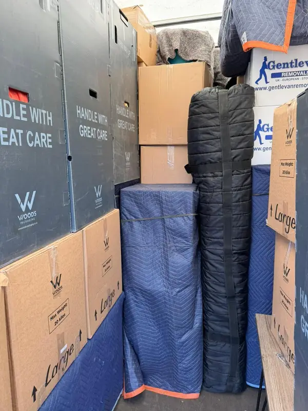 Interior of a loaded removal van with Gentlevan branded cartons, blanket-wrapped furniture and Handle With Great Care containers