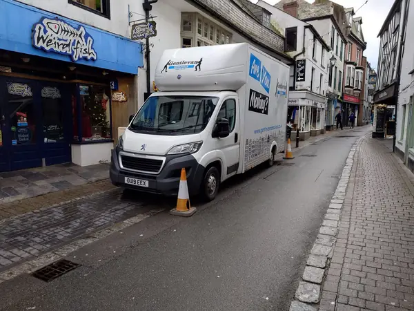 Gentlevan Luton removal van coned off on a narrow market town street, loading outside a shopfront
