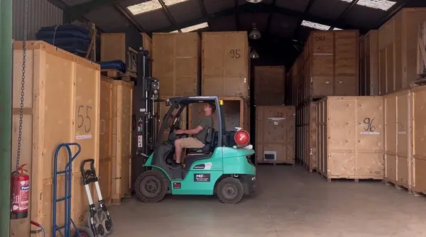 Numbered timber storage containers stacked in the Gentlevan warehouse, forklift moving one into place