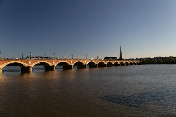 Pont de Pierre bridge at golden hour with tram and pedestrians over the Garonne River, Bordeaux, France