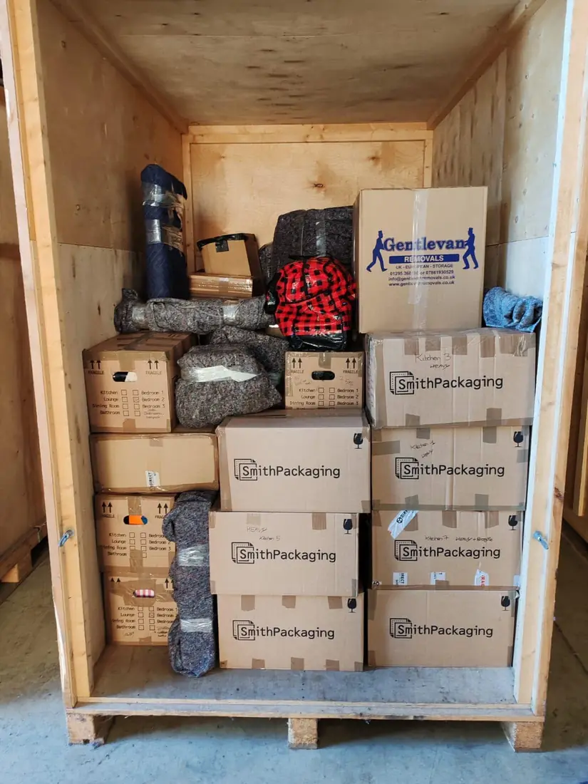 Inside a timber storage container packed with labelled cartons and blanket wrapped furniture at the Gentlevan Removals store