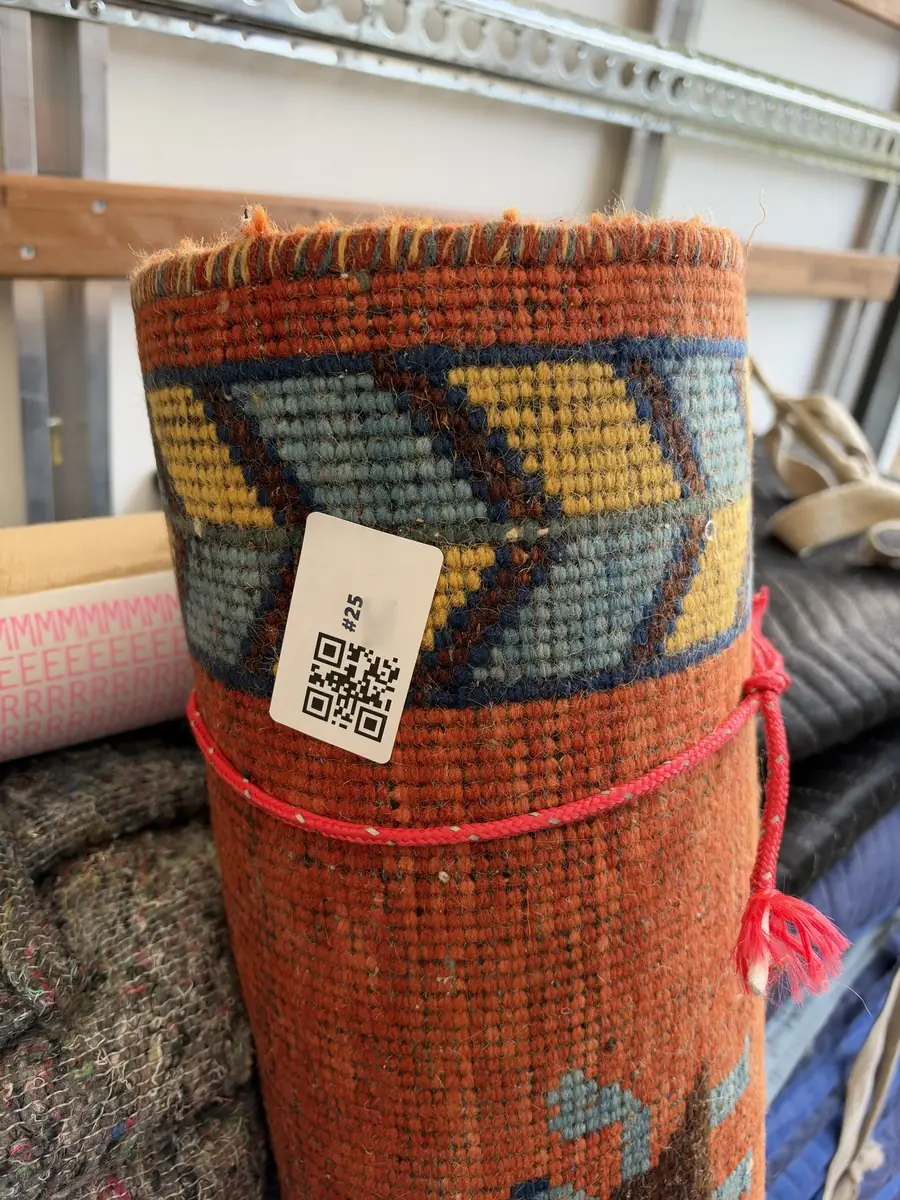 A Gentlevan numbered QR inventory label on a rolled rug ready for loading