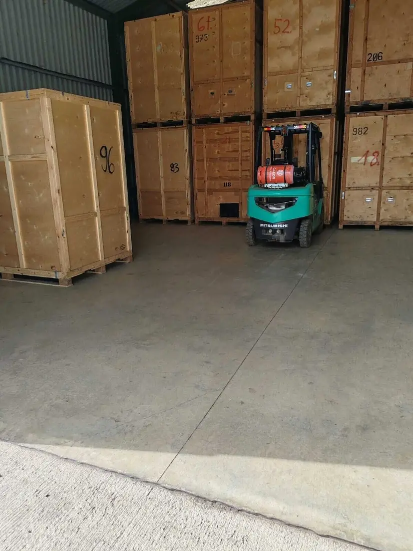 Numbered timber storage containers stacked in the Gentlevan Removals warehouse with a forklift