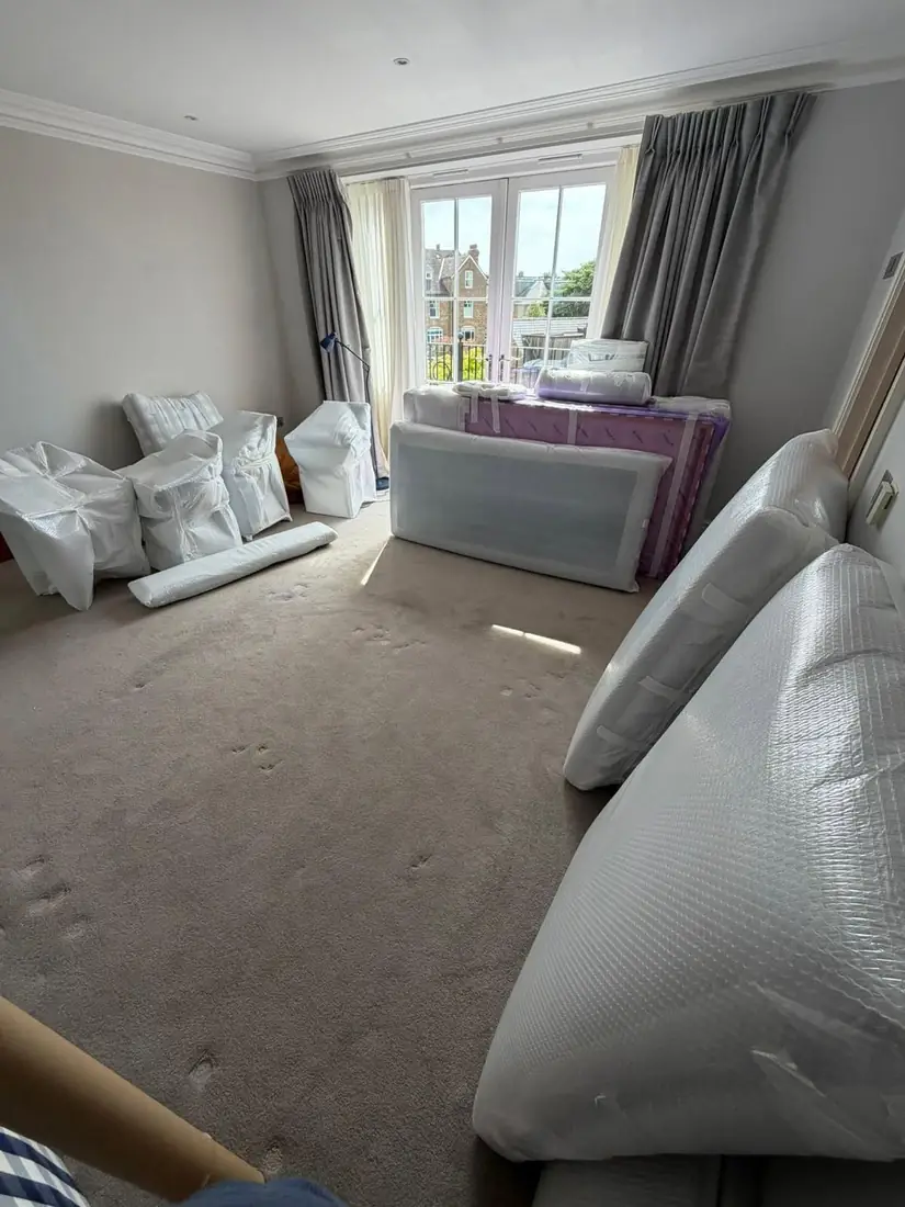 Bedroom furniture, mattresses and armchairs in white protective covers and export wrapping before loading